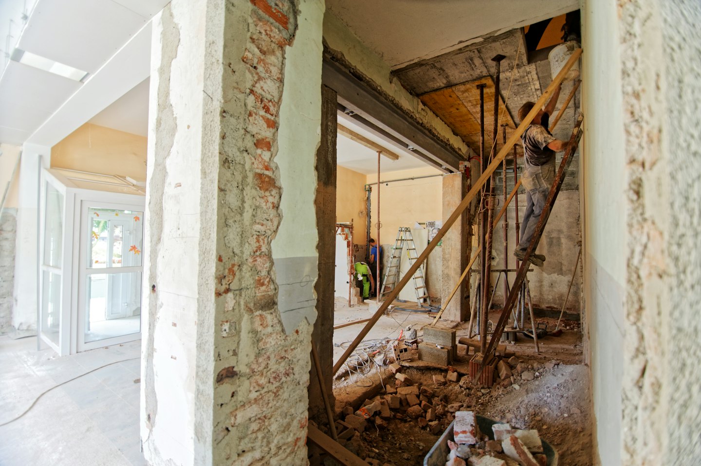 Construction workers renovating a building with exposed brick walls.