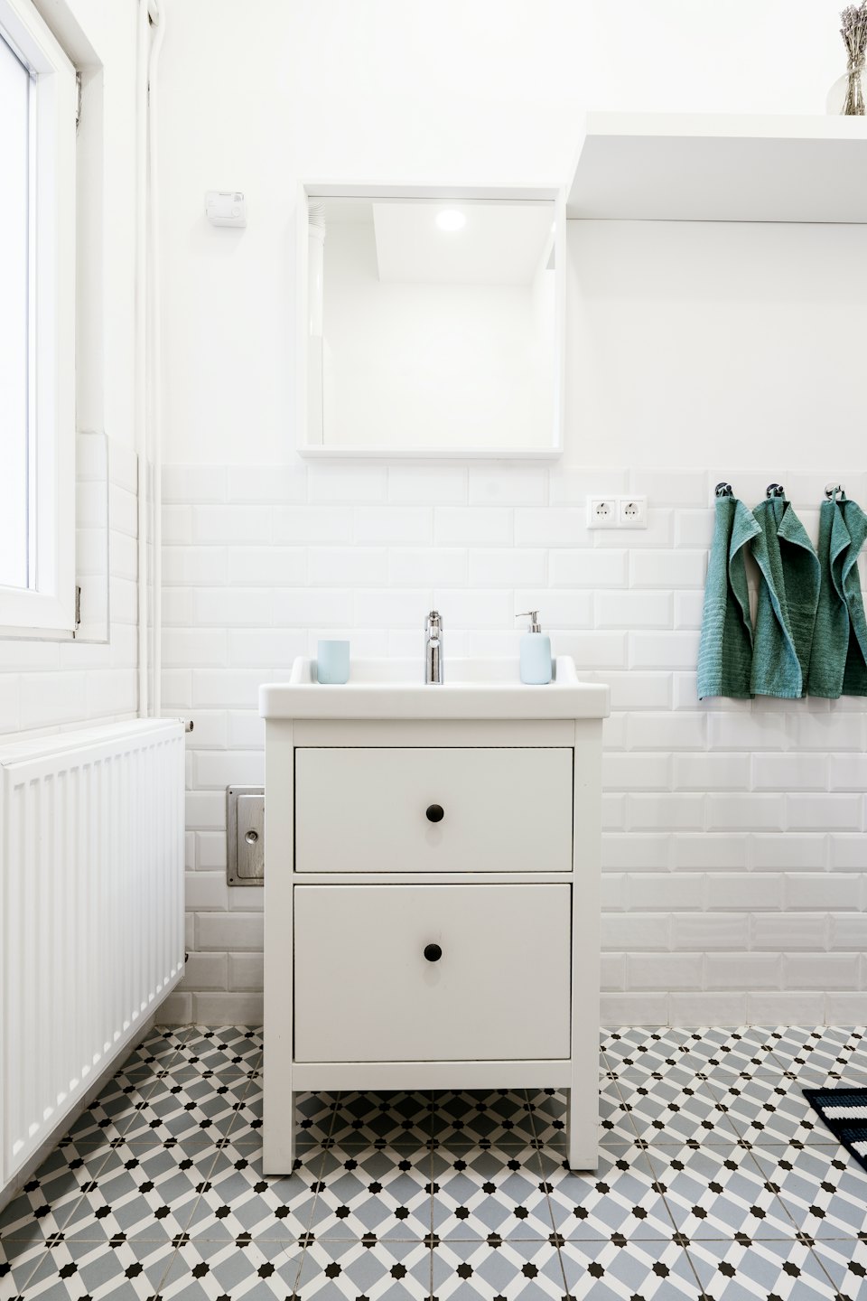 Modern bathroom with white vanity and geometric floor tiles.