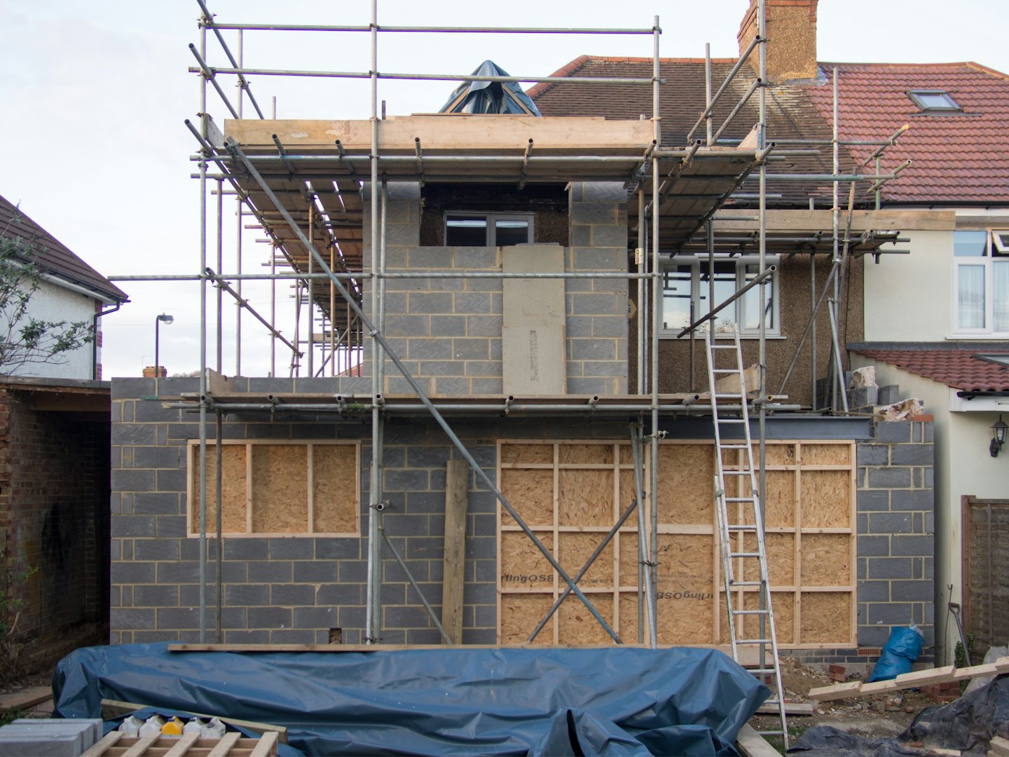 Cinder block house extension under construction with scaffolding.