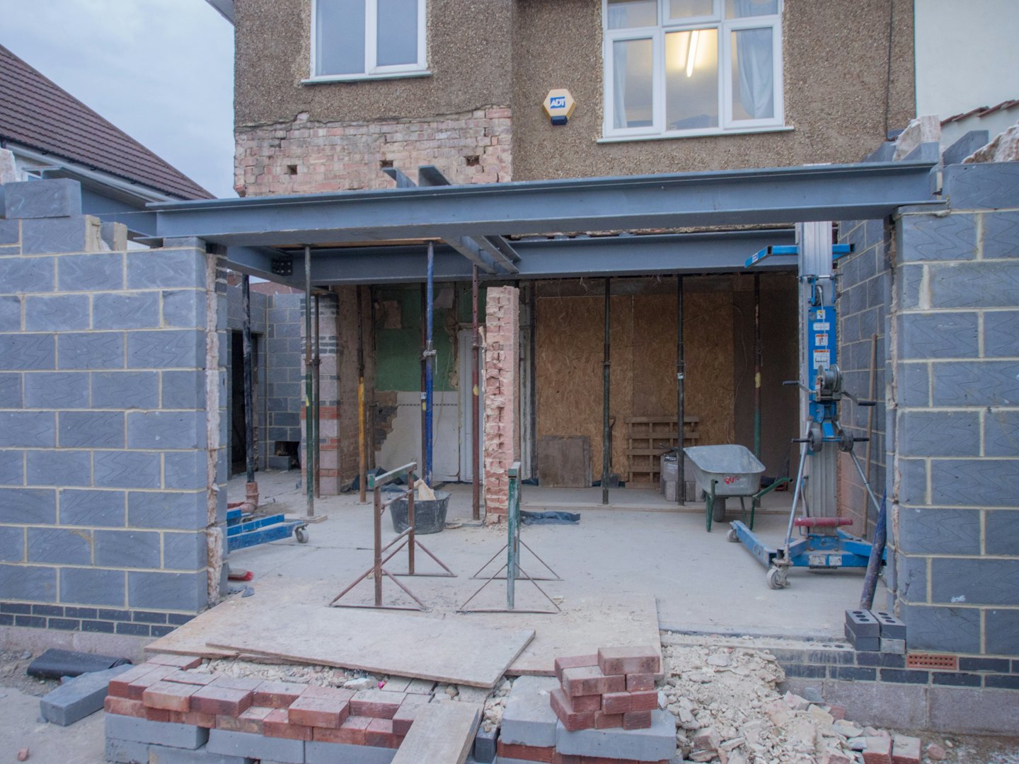Construction of a grey concrete block house extension with steel beam.