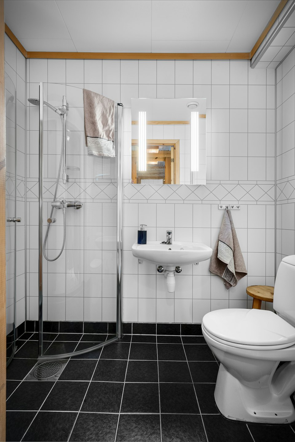 Modern bathroom with white tiled walls and a glass shower.