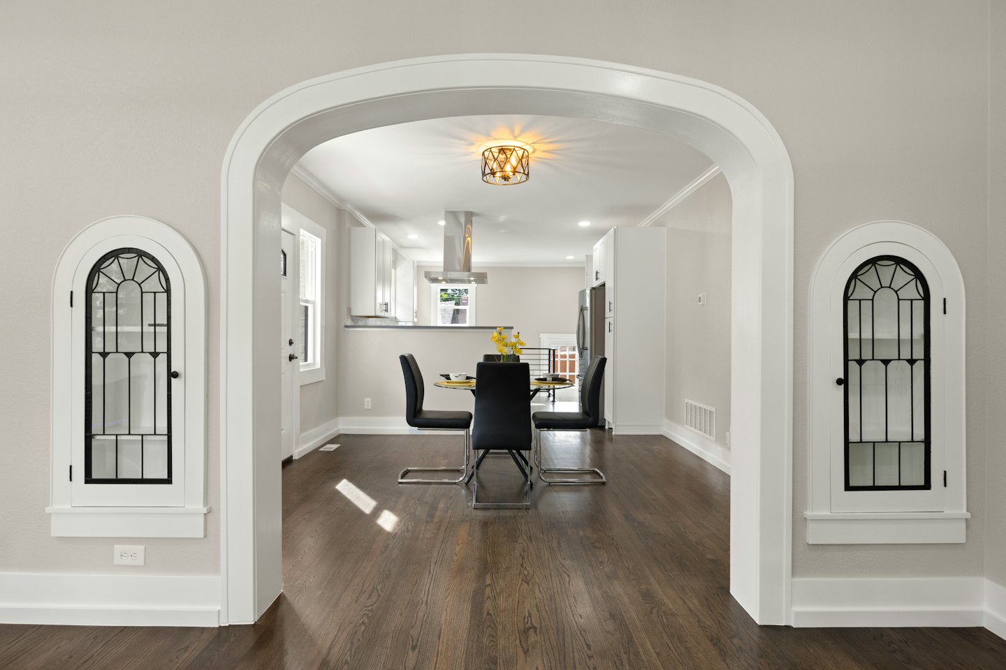 Open-concept dining and kitchen through arched doorway.